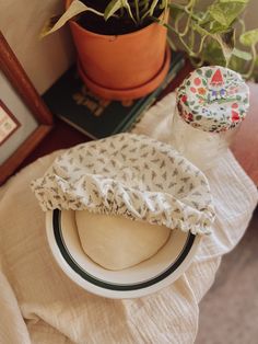 a white bowl sitting on top of a table next to a potted plant