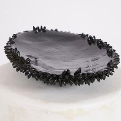 a black plate sitting on top of a white cake stand next to a white wall