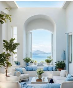 a living room filled with lots of white furniture and blue pillows on top of it