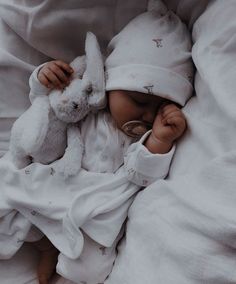 a baby is laying in bed with a stuffed animal