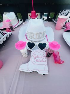 a table topped with pink and white hats and personalized items on top of it