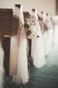 flowers are tied to the pews at a wedding ceremony in white tulle and burlock