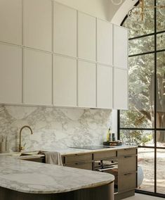 a kitchen with white cabinets and marble counter tops, along with an island in the middle