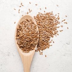 a wooden spoon filled with seeds on top of a white surface