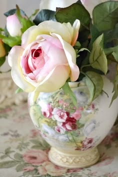 a vase filled with pink and white flowers on top of a floral covered table cloth