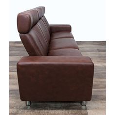 a brown leather reclining chair sitting on top of a wooden floor next to a white wall