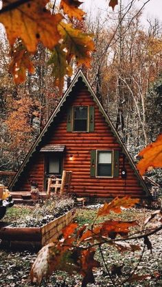 a small log cabin in the woods with a yellow truck parked next to it and autumn leaves on the ground