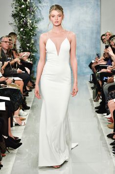 a woman walking down a runway in a white dress