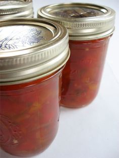 three jars filled with pickles sitting next to each other