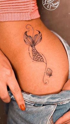 a woman's stomach with a fish tattoo on her belly and the bottom part of her lower back