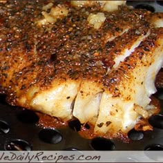 a piece of meat is being cooked in a frying pan with spices on it