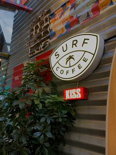 a surf coffee sign on the side of a building next to a potted plant