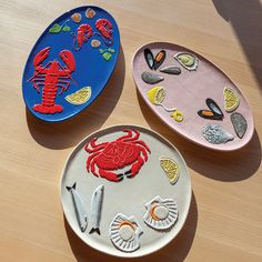 three plates with different designs on them sitting on top of a wooden table next to each other