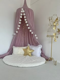 a white bed topped with pillows and a gold star next to a purple drape