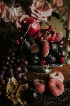 a bowl filled with fruit sitting on top of a table next to flowers and candles