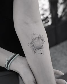 a woman's arm with a shell tattoo on the left side of her arm