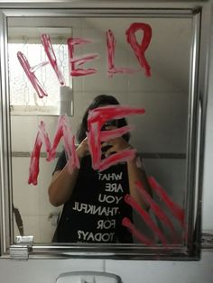 a woman taking a selfie in a mirror with the words help painted on it