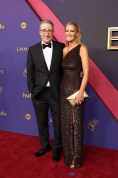 a man and woman in formal wear standing on a red carpet at an event together