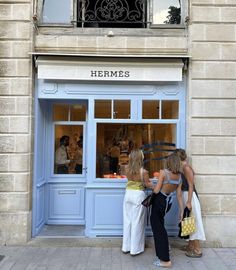 two women are standing in front of a store