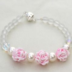 a bracelet with pink roses and pearls on it