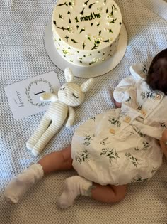 a baby laying on the floor next to a cake