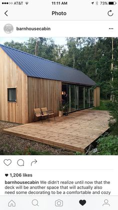 a wooden deck with two chairs on it next to a small house in the woods