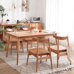 a dining room table with chairs and a potted plant in the corner next to it