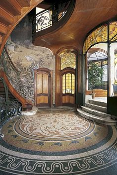 an elaborately designed entryway with stairs and circular tiles on the floor is pictured in this photograph