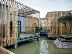 an outdoor area with water and bamboo screens on the walls, along with plants in pots