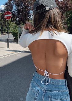 a woman with her back turned to the camera, wearing jeans and a baseball cap