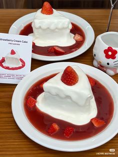 two white plates topped with dessert covered in strawberry cream and whipped cream next to a hello kitty mug