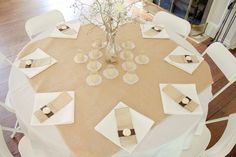 the table is set with white linens and place settings