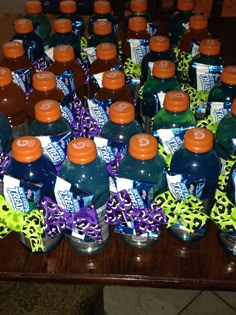 there are many bottles of soda on the table with purple and green ribbons around them