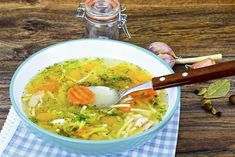 a bowl of soup with carrots, broccoli and other vegetables in it