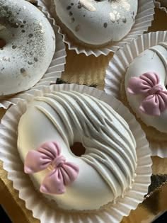 four donuts with white frosting and pink bows on them