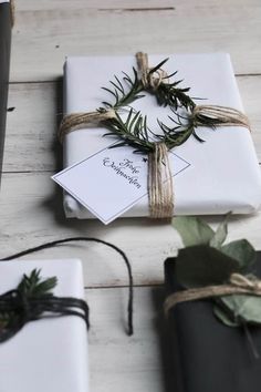 two wrapped presents tied with twine on top of a wooden table next to each other