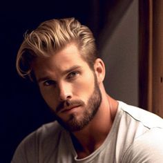 a man with blonde hair and beard wearing a white t - shirt looking at the camera