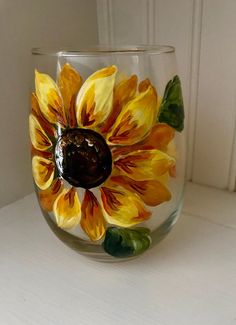 a glass vase with yellow and orange flowers painted on the inside, sitting on a white surface