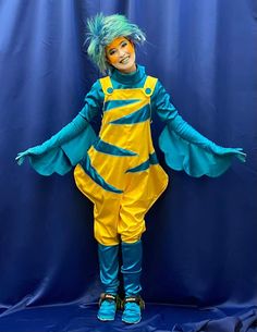 a person in a blue and yellow costume posing for a photo on a blue background