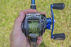 a person holding a fishing reel with grass on it