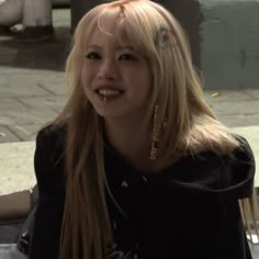 a woman with long blonde hair and piercings on her ears smiles at the camera