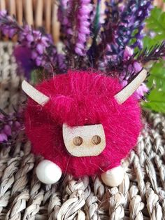 a red and white stuffed animal sitting next to purple flowers