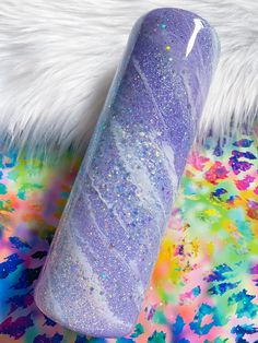 a long purple tube sitting on top of a colorful carpet with white fur around it