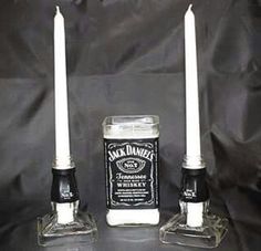 two candles sitting next to each other in front of a black cloth covered background with the words jack daniels written on it