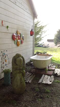 a bath tub sitting in the middle of a yard next to a wall with decorations on it