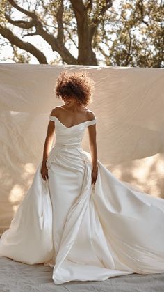 a woman in a white wedding dress standing on a bed with her back to the camera