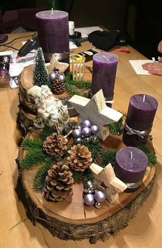 a wooden table topped with purple candles and pine cones on top of it's sides