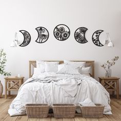 a bed with white sheets and pillows in front of three wall hangings above it