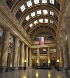 the inside of a large building with columns and an american flag hanging from the ceiling