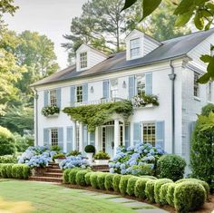 a large white house with blue shutters and flowers